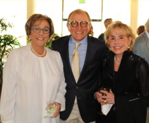 three people pose for a photo while enjoying cocktails on a patio