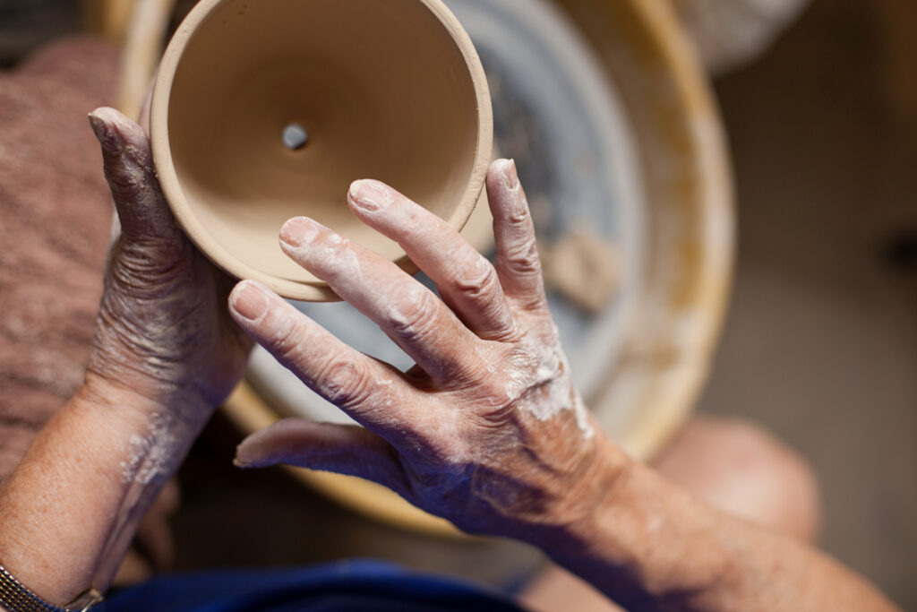 Hands shaping a clay pot on a pottery wheel