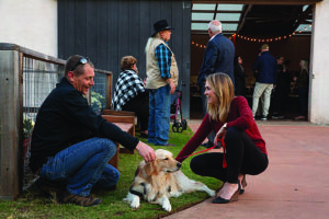 people take a break from celebrating and pet a dog at an event for animal advocates