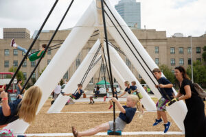 Children swing across a modern scuptural structure