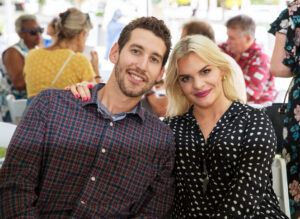 a seated couple smiles together in an outdoor setting