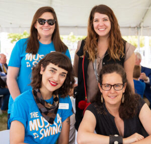 group of four women pose together for a photo in an outdoor setting
