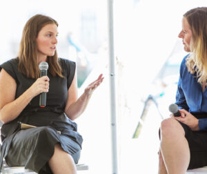 two women - Rebecca Taylor and Louisa McCune - join in conversation using a microphone during an outdoor event in Oklahoma City