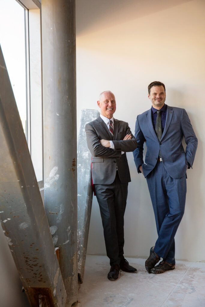 two men pose inside an industrial site