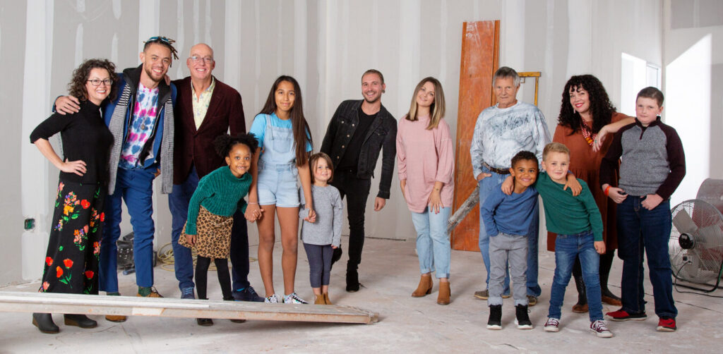 I diverse group of children and adults pose in an industrial setting