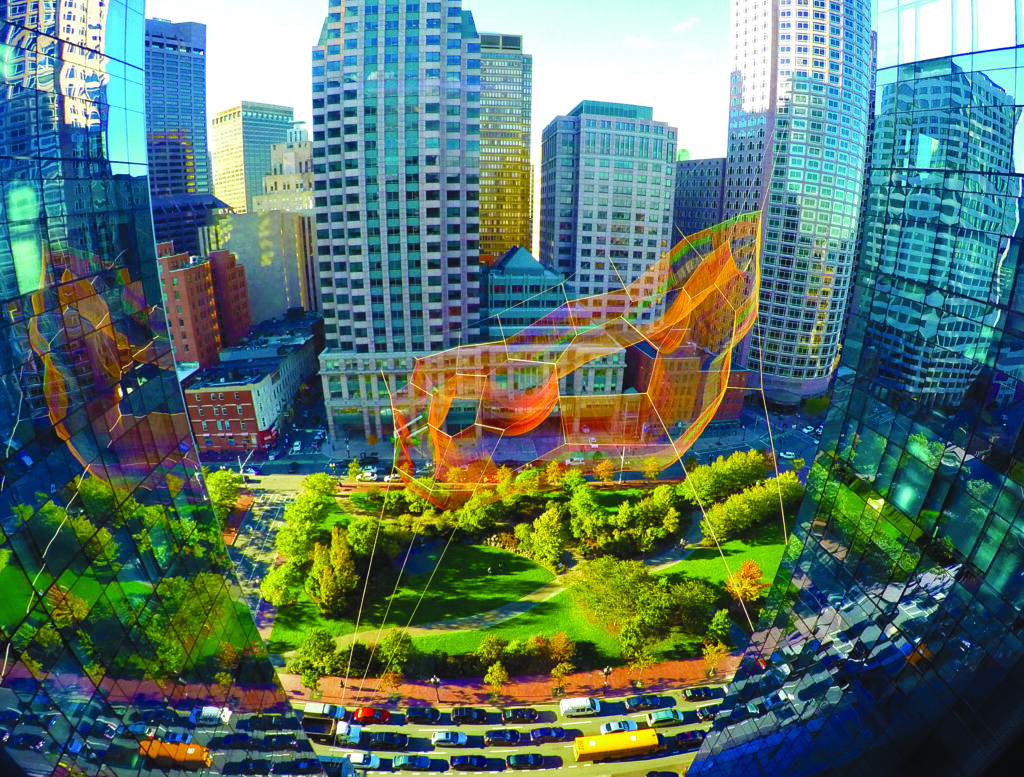 View of a downtown city park surrounded by glass office towers, with an orange mesh aerial art installation suspended above the trees and pathways.