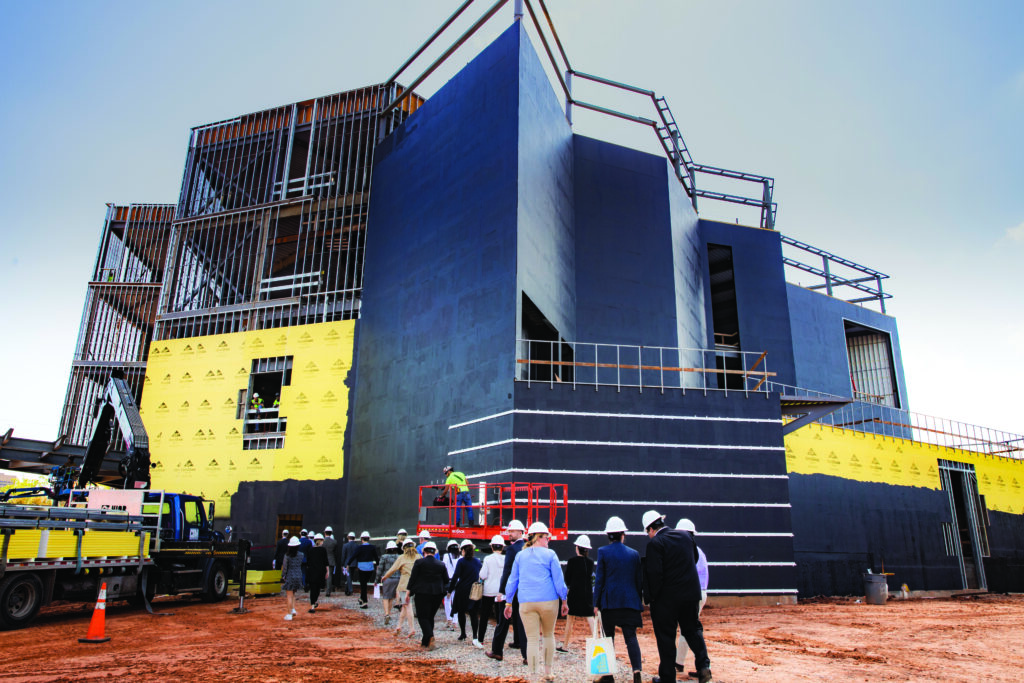 people in hardhats head toward the impressive, under-construction building for the new Oklahoma Contemporary Arts Center