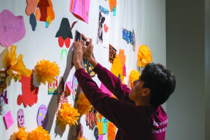an art patron participates in a Celebration of Latino Culture Event by adding personal touches to a community ofrenda, or alter, designed to welcome the dead during Día de los Muertos