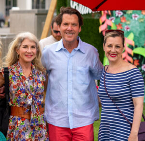 three people pose in summer attire in an outdoor setting