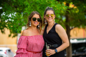 two women pose outdoors in summer attire