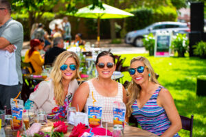A group of three women seated at a table during an outdoor brunch event