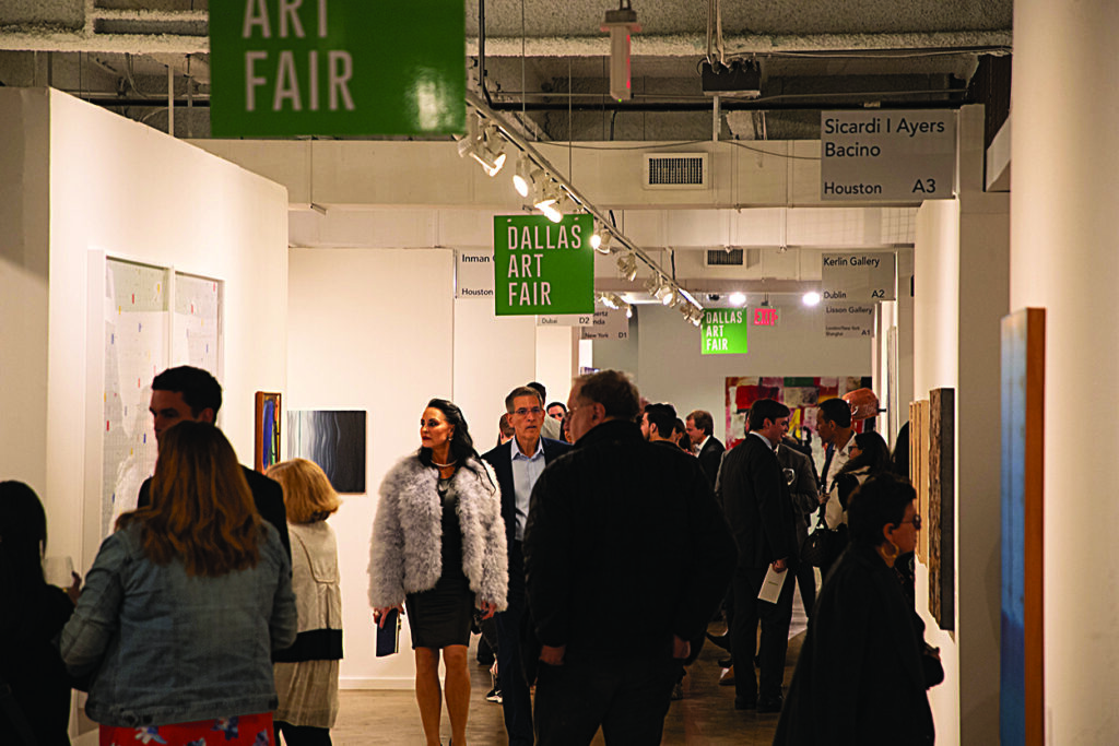 a group of people move through a hallway at the Dallas Art Fair