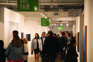 a group of people move through a hallway at the Dallas Art Fair