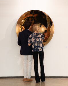 two people look at a reflective artwork