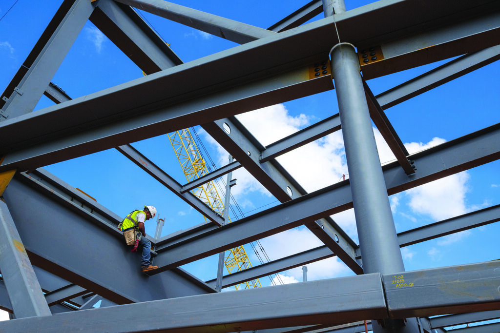 workers in hardhats construct the foundation of a new building from atop beams in the sky