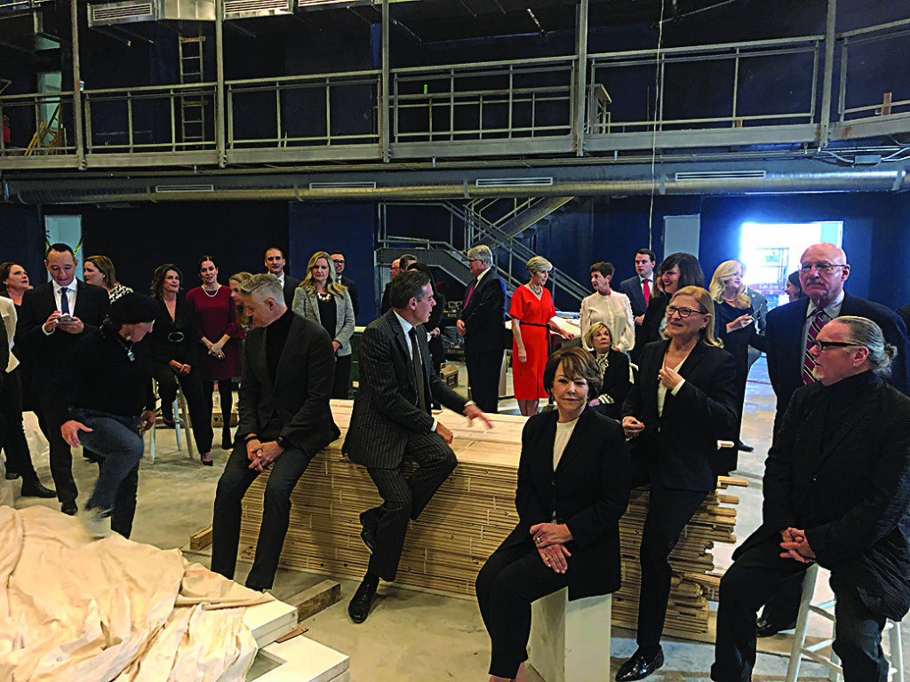 a large group of people gather in an industrial space for a group photo