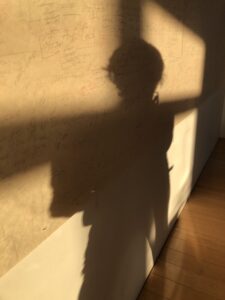 Shadow of American dancer, choreographer, director, and author Twyla Tharp, bisected by a windowpane washed in golden light