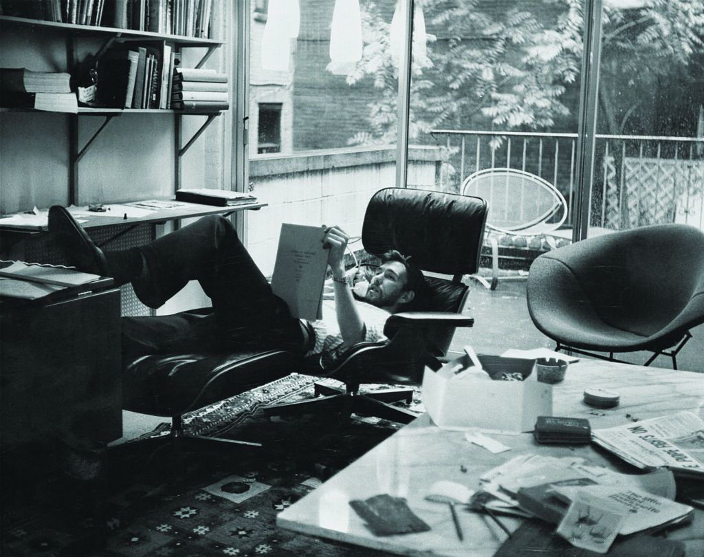 a man in a black chair relaxes and reclines while reviewing a notebook