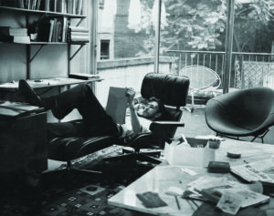 a man in a black chair relaxes and reclines while reviewing a notebook