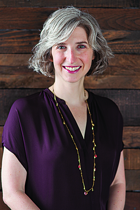 A woman poses for a portrait in front of a wooden wall