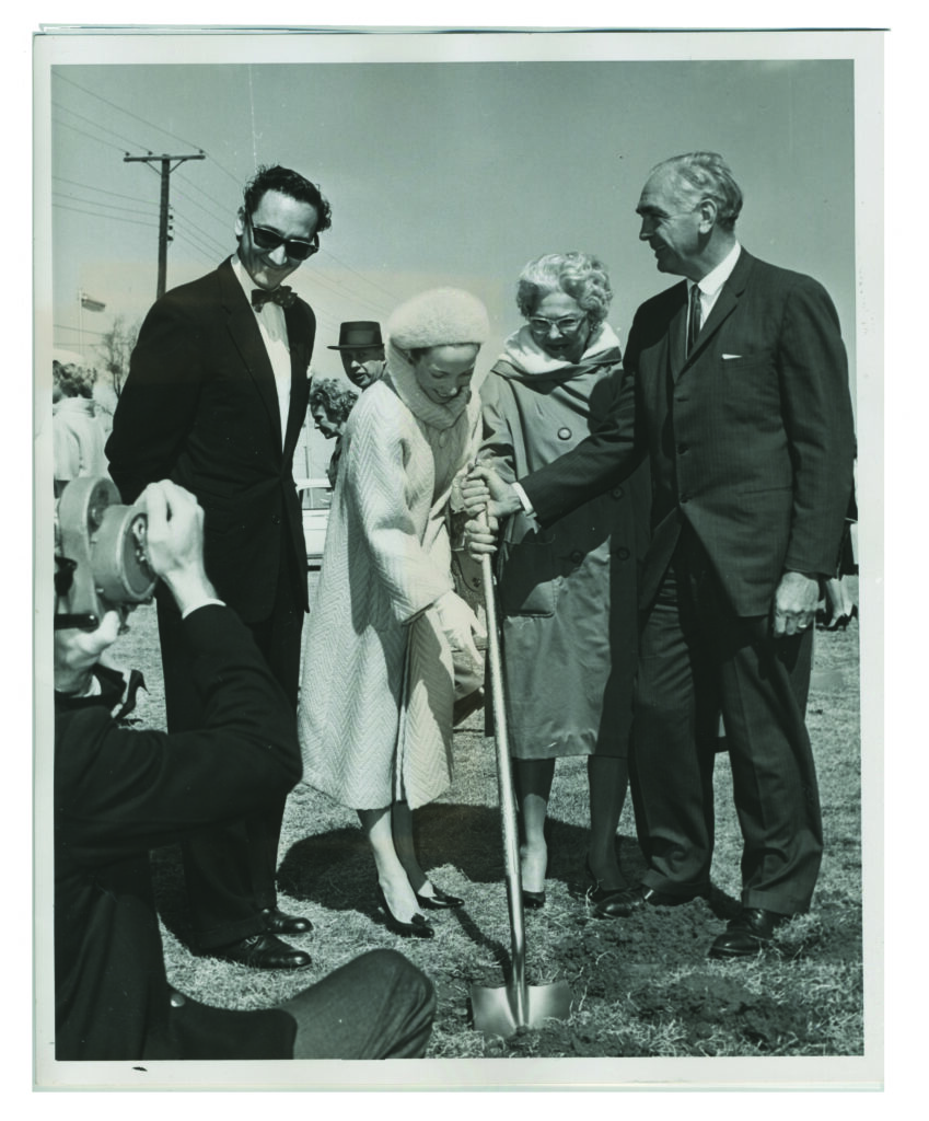People gather round a shovel at a groundbreaking event
