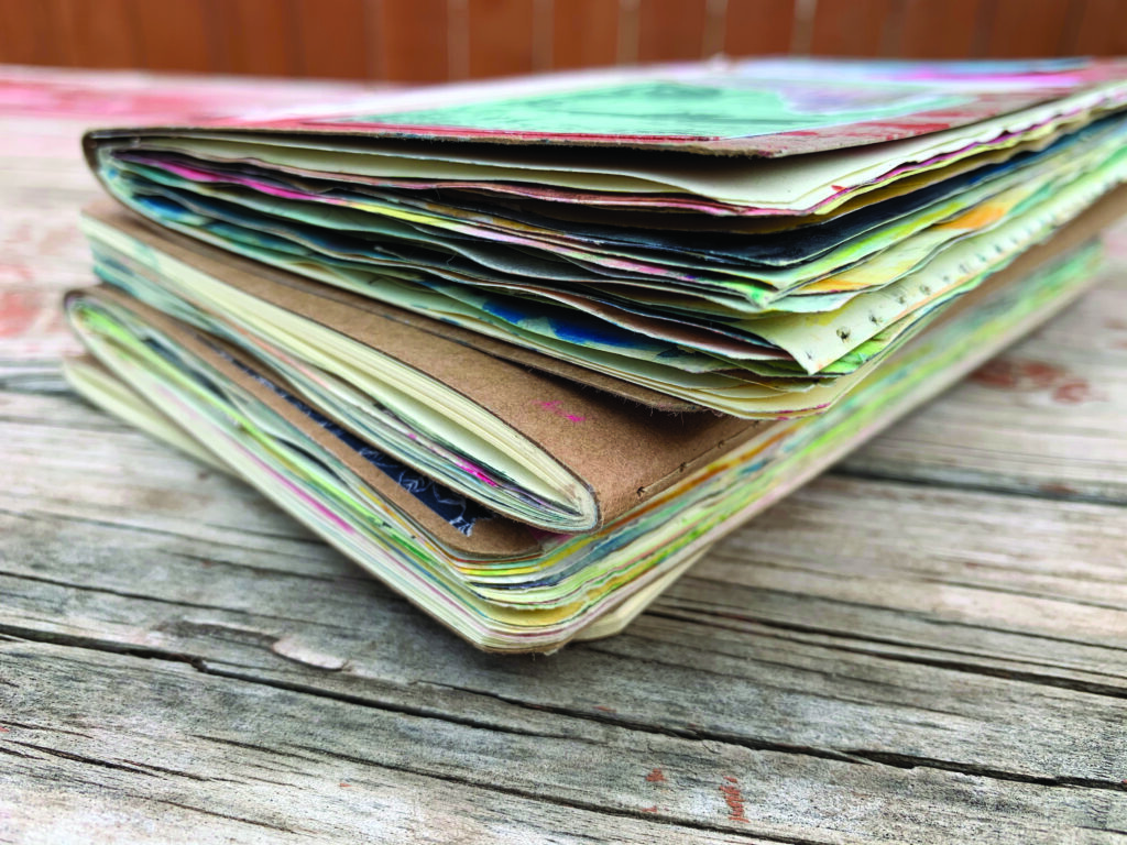 a stack art notebooks on a table