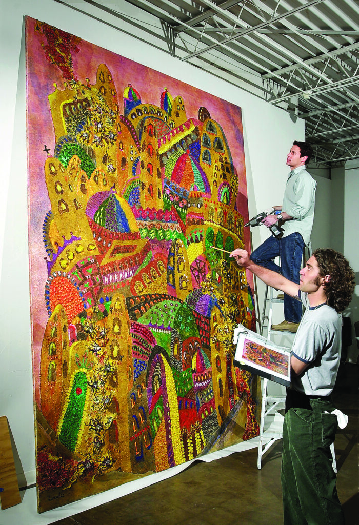two men hang a large artwork at a museum