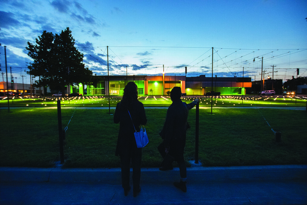 two museum patrons look out over a modern outdoor art installation at twilight
