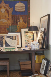 a desk against a wall scattered with artwork