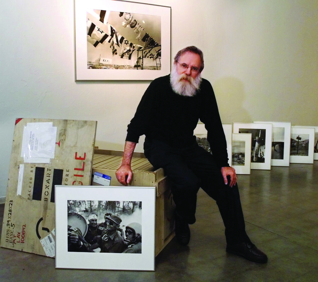 a photographer poses with his works in a clean studio space