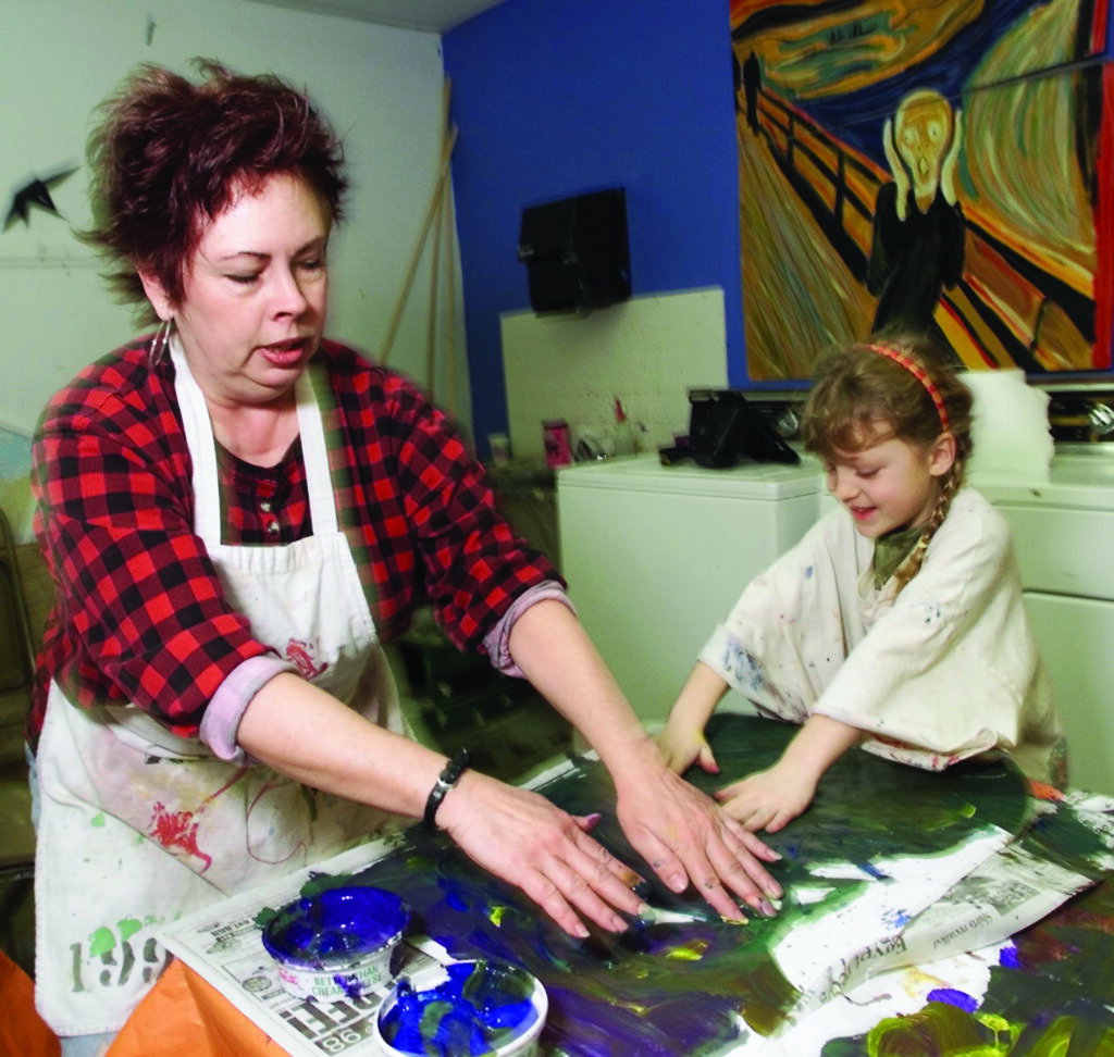 an instructor helps a student during an art class