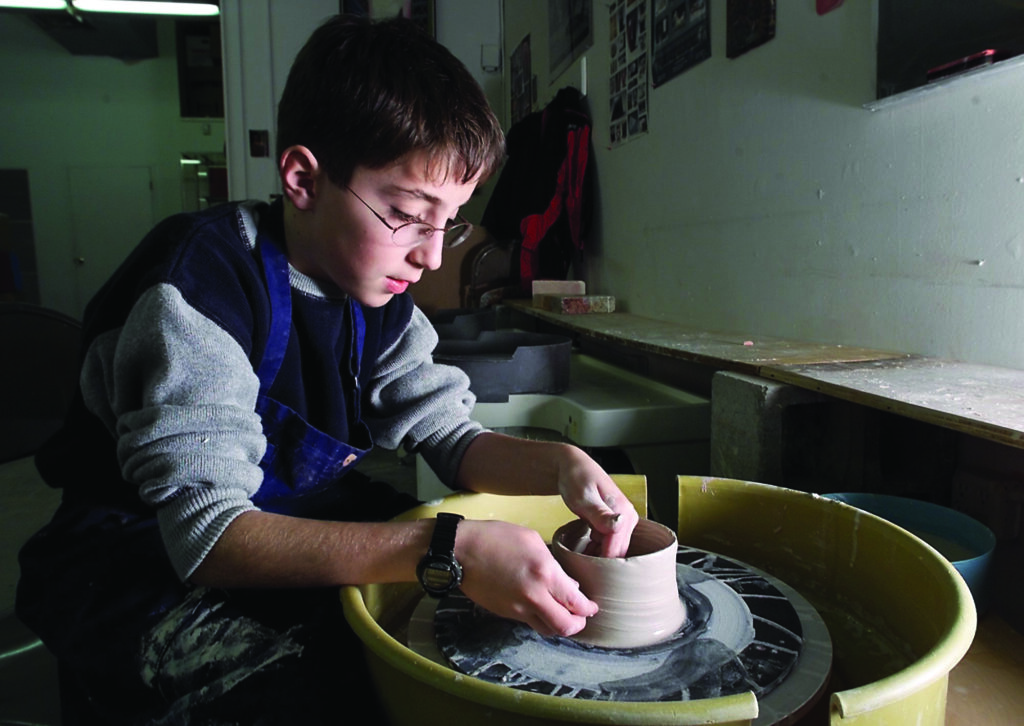 a boy takes a turn on a pottery wheel