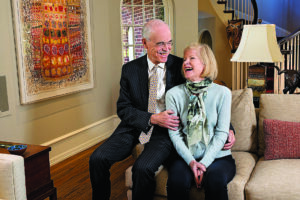 Philanthropists Charles and Renate Wiggin sit and smile while looking at one another affectionately