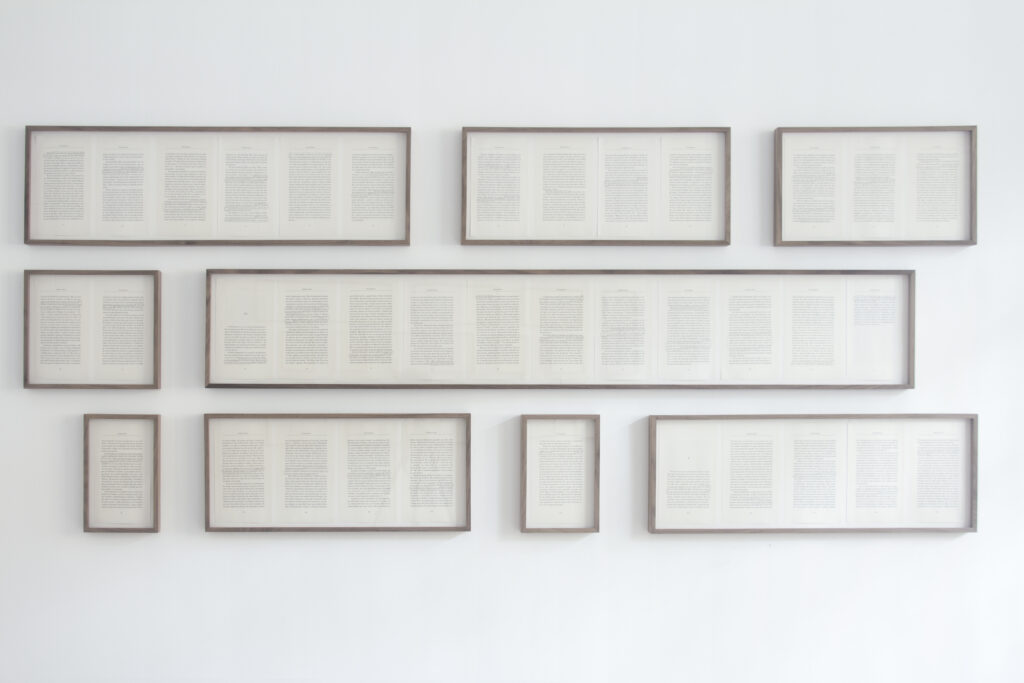 varying sizes of framed text are hung on a gallery wall