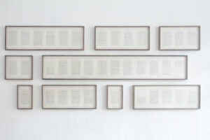 varying sizes of framed text are hung on a gallery wall
