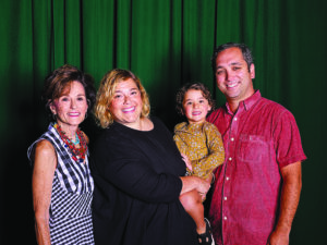a group of people pose in front of a green curtain