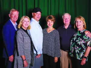 a group of people pose in front of a green curtain