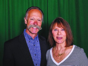 two people pose in front of a green curtain