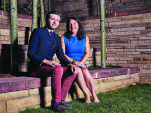 two people sit in an outdoor garden setting and pose for a picture