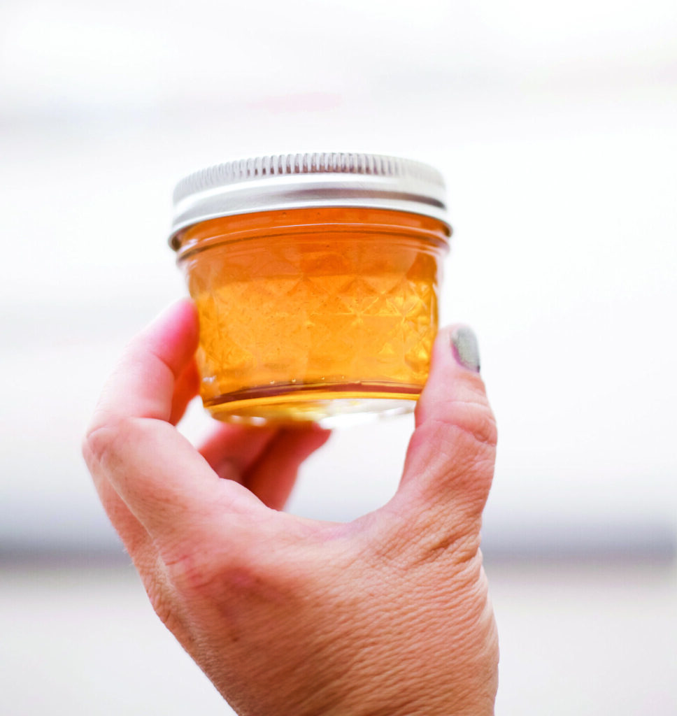 a hand holds up a jar of honey