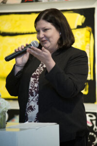 a woman takes the podium and address a crowd