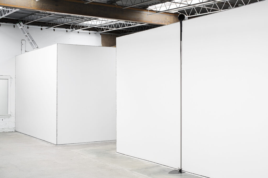 stark white walls with charcoal-lined edges make an artistic statement in an industrial gallery