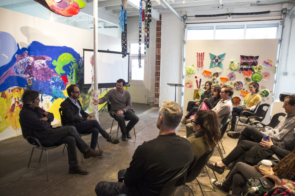 three people engage in a conversation panel at an art event